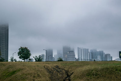 Scenic view of field by buildings against sky