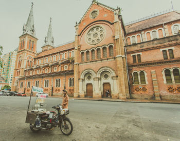 Man riding motorcycle on street amidst buildings in city