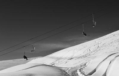 Low angle view of ski lift over snowcapped mountain against sky