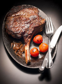 High angle view of roasted meat chop and cherry tomatoes in plate