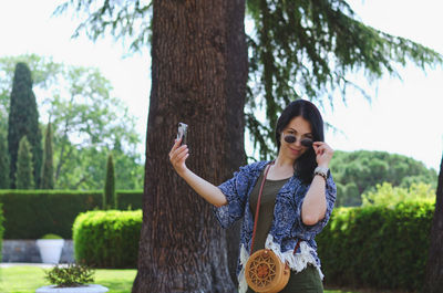 Young happy business woman relaxing in city, park. using phone. selfie. technology. summer vacation