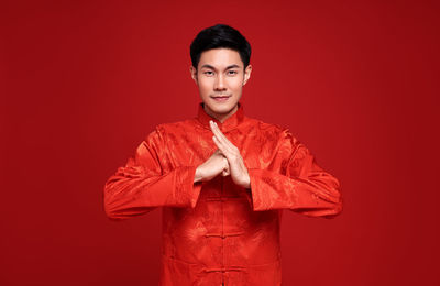 Portrait of smiling young man against red background