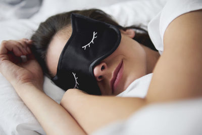 Portrait of young woman with sleep mask in bed