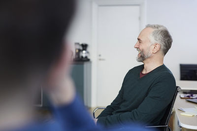 Smiling mature businessman sitting with colleague at office