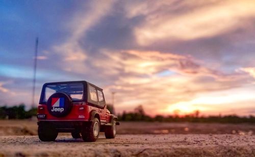 Vintage car on field against sky during sunset