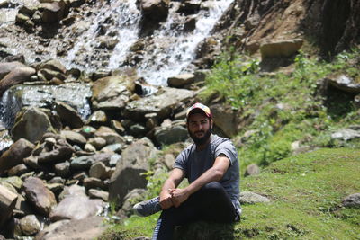 Full length of young man sitting on rocks