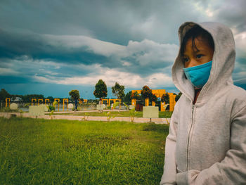 Portrait of young woman standing on field against sky