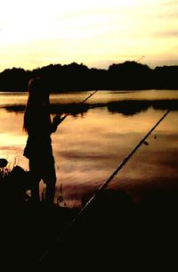 Silhouette of people in water at sunset