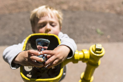 High angle view of boy opening faucet