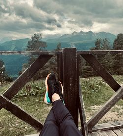 Low section of man standing by railing against sky