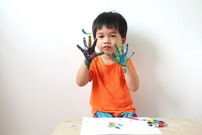 Asian boy is learning to use watercolors by painting on his hands.