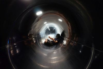 Man wearing gorilla mask while sitting in illuminated tunnel