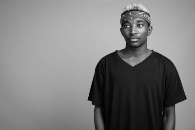 Portrait of young man looking away against white background