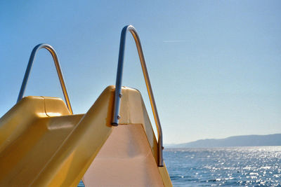 Close-up of yellow ship in sea against clear sky