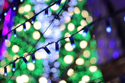 Low angle view of illuminated lighting equipment hanging at night