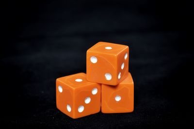 Close-up of orange dice on black background