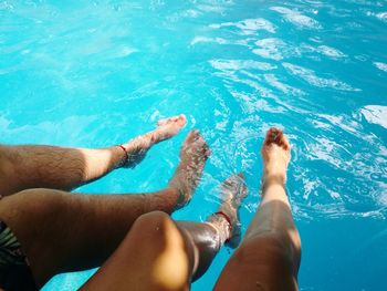 Low section of couple relaxing in swimming pool