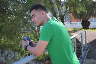 Side view of young man using mobile phone outdoors