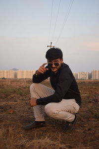 Young man using mobile phone while sitting on field