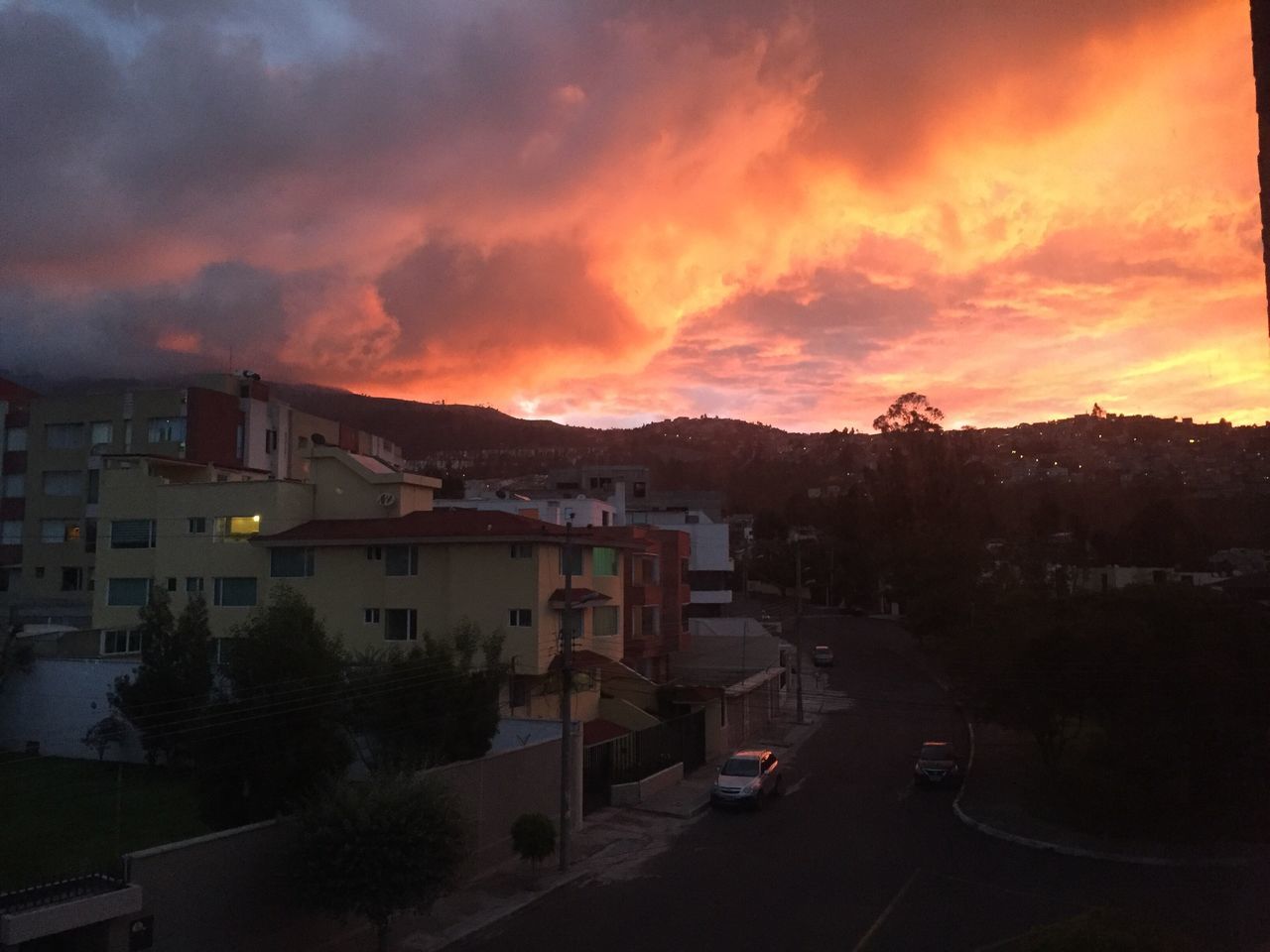 sunset, building exterior, sky, architecture, built structure, orange color, cloud - sky, car, transportation, house, road, land vehicle, residential structure, high angle view, city, residential building, mode of transport, street, dusk, cloudy