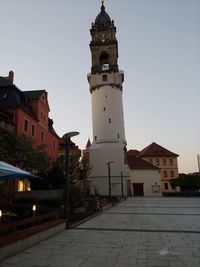 Clock tower amidst buildings in city against sky