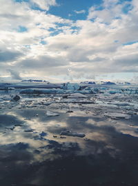 Scenic view of sea with icebergs against cloudy sky