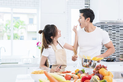 Young couple cooking food while standing in kitchen