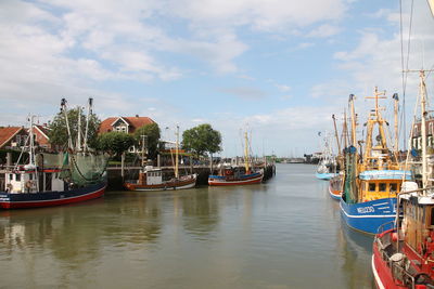 Boats moored in canal against sky in city