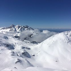 Scenic view of snowcapped mountains against blue sky