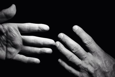 Close-up of hands reaching against black background