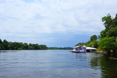 Scenic view of river by buildings against sky