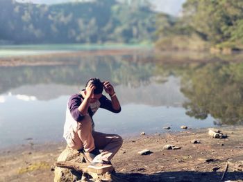 Side view of man sitting at lakeshore