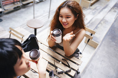 Lesbian couple holding disposable coffee cup sitting at cafe