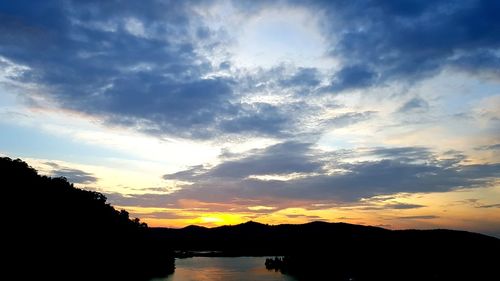 Silhouette trees by lake against sky during sunset