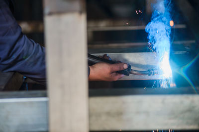 Cropped hand of man welding metal at workshop