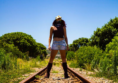 Rear view of man standing on railroad track against sky
