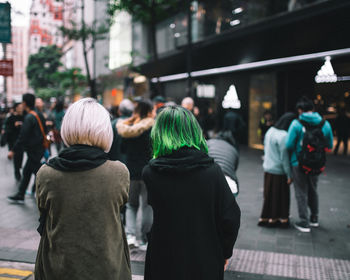 Rear view of people walking on sidewalk