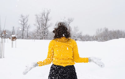 Winter season. young brunette woman playing with snow in park