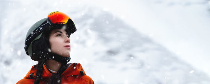 Low angle view of young woman standing on snow