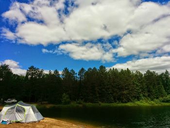 Trees on landscape against cloudy sky