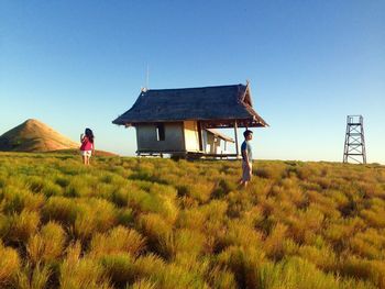 Person standing on grassy field against clear sky