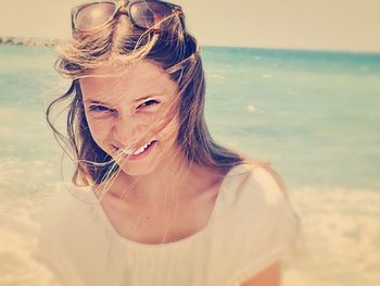 Close-up portrait of young woman standing on beach