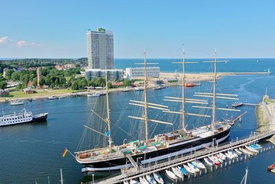 Sailboats moored at harbor in city against sky