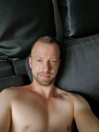 Portrait of shirtless man lying on sofa at home