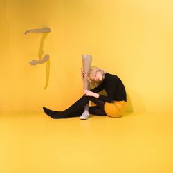 Young woman wearing hat against yellow background