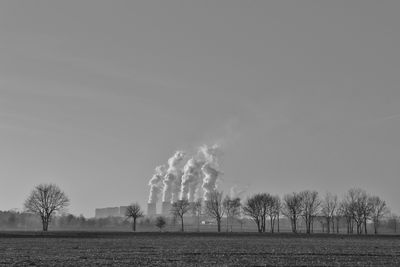 Smoke emitting from factory against clear sky