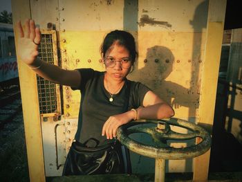 Portrait of young woman standing against yellow metal wall