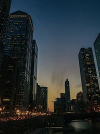 Illuminated buildings in city against sky at dusk