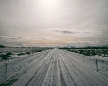 Scenic view of snow covered road against sky during sunset