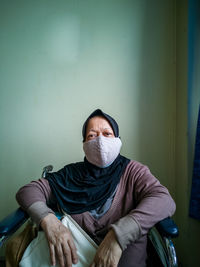 Portrait of man sitting against wall